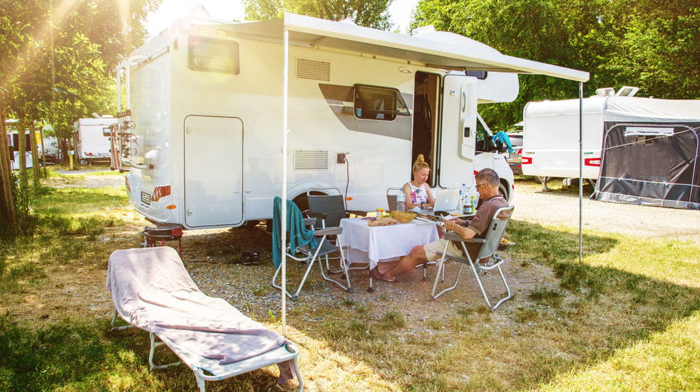 Plan your first motorhome holiday; couple relaxing outside motorhome